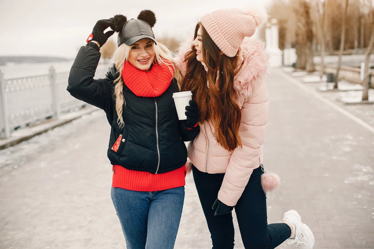 Две девушки в зимней одежде: черная куртка и розовый пуховик с мехом